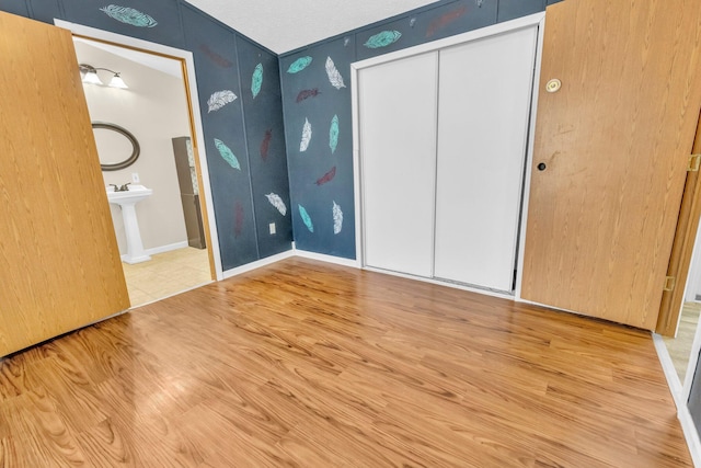 unfurnished bedroom featuring a closet, ensuite bathroom, hardwood / wood-style floors, and sink