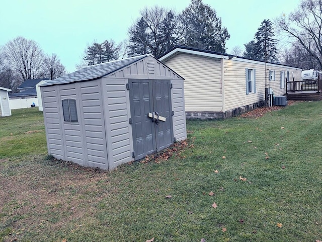 view of outdoor structure with a lawn and central AC unit