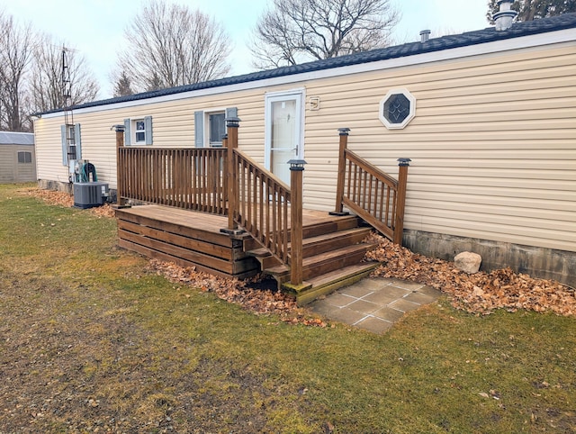 rear view of house with central AC unit and a lawn