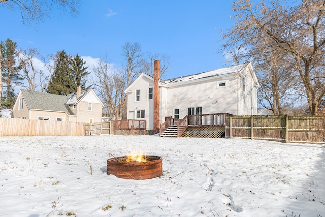 snow covered house featuring a fire pit and a deck