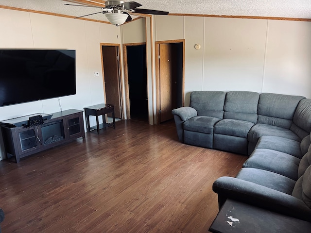 living room featuring ceiling fan, dark hardwood / wood-style flooring, ornamental molding, and a textured ceiling