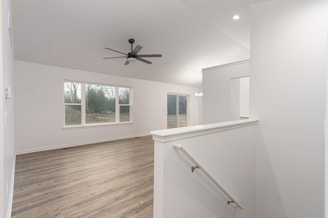 spare room with hardwood / wood-style flooring, vaulted ceiling, and ceiling fan with notable chandelier