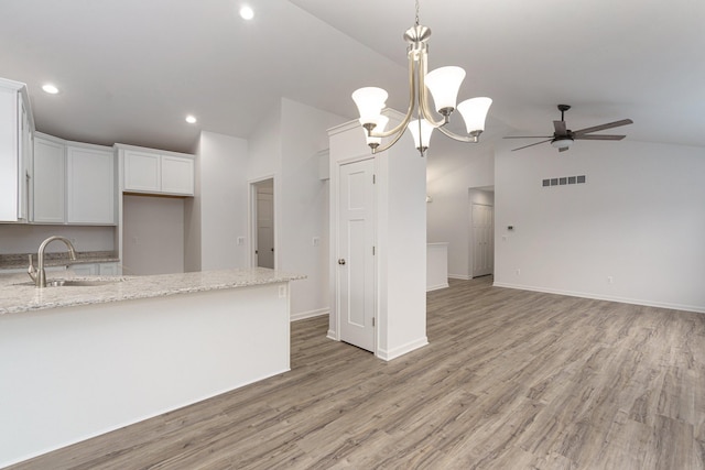 kitchen featuring white cabinetry, lofted ceiling, sink, light stone counters, and light hardwood / wood-style flooring