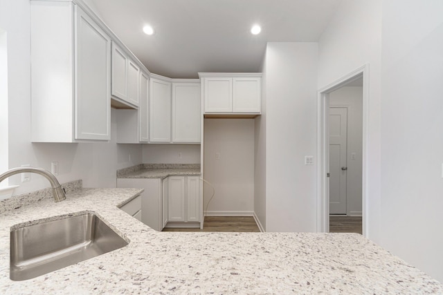 kitchen featuring white cabinetry, sink, and light stone counters