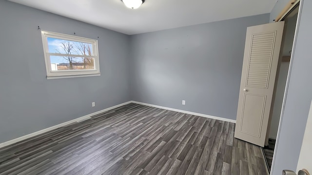 unfurnished bedroom featuring dark wood-type flooring and a closet