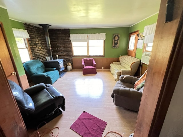 living room featuring light hardwood / wood-style flooring, a wood stove, and brick wall