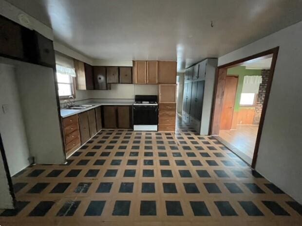 kitchen with sink, white range, and tile patterned flooring