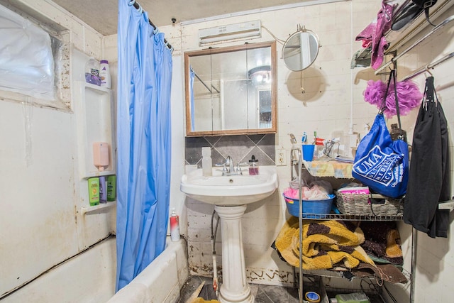 bathroom featuring decorative backsplash, shower / bath combo with shower curtain, and sink