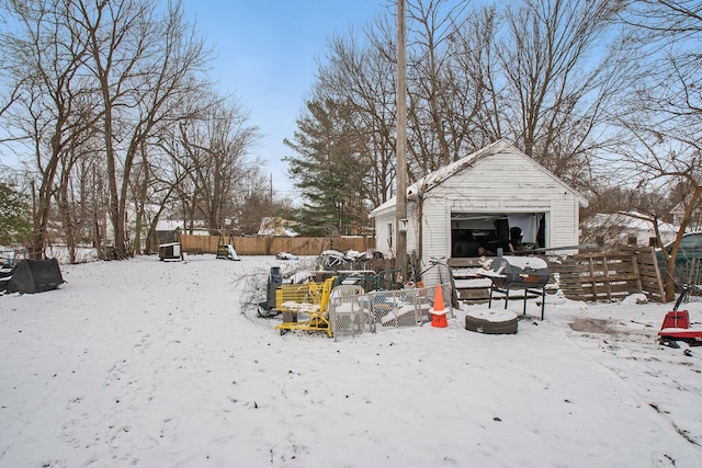 snowy yard with a garage and an outdoor structure