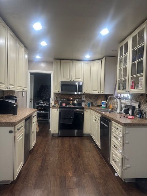 1220 Elford Ct, Grosse Pointe Woods, MI 48236 - kitchen featuring appliances with stainless steel finishes, dark wood-style flooring, backsplash, glass insert cabinets, and recessed lighting