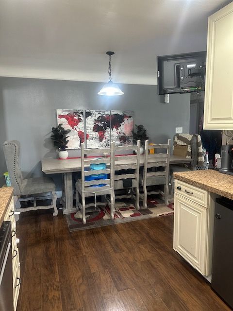 kitchen featuring cream cabinetry, decorative light fixtures, dishwasher, and dark wood-type flooring