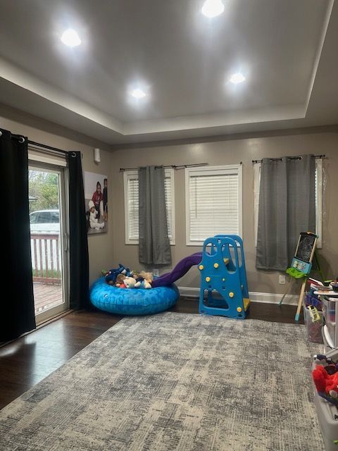 rec room with a raised ceiling and dark wood-type flooring