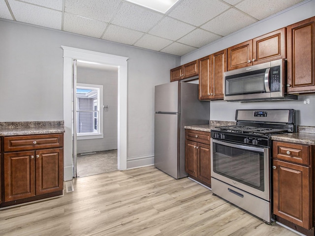 kitchen featuring light wood-type flooring, stainless steel appliances, and a drop ceiling