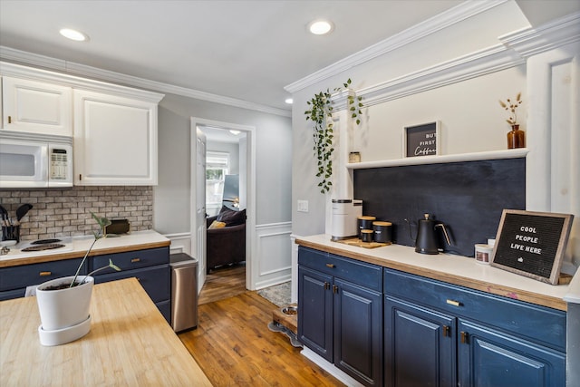 kitchen featuring hardwood / wood-style floors, white cabinets, ornamental molding, and blue cabinets