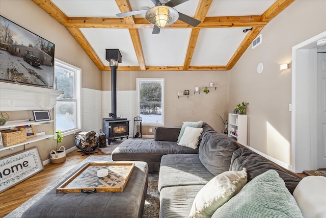 living room with a wood stove, ceiling fan, hardwood / wood-style floors, and a healthy amount of sunlight