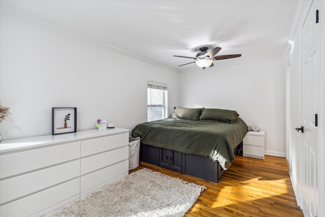 bedroom featuring ceiling fan, crown molding, and dark wood-type flooring