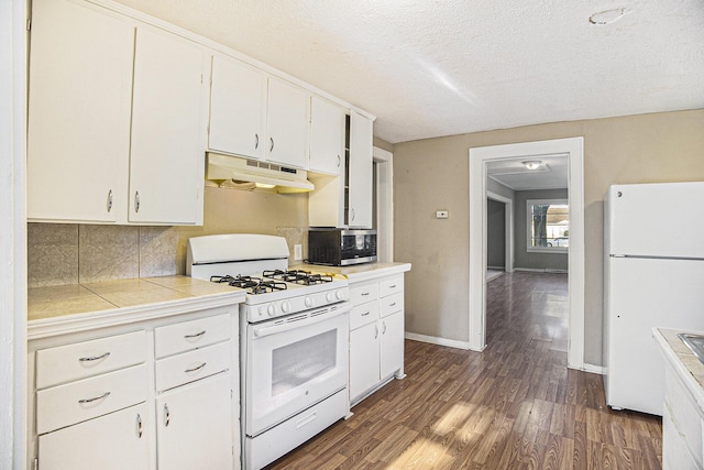 kitchen with tasteful backsplash, white appliances, white cabinets, dark hardwood / wood-style floors, and tile counters