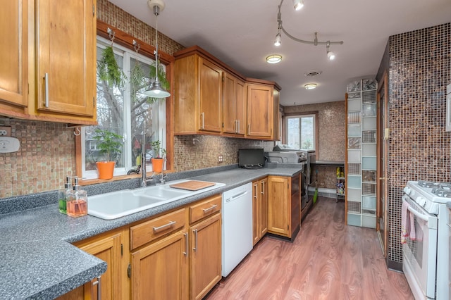 kitchen featuring tasteful backsplash, white appliances, sink, decorative light fixtures, and hardwood / wood-style floors