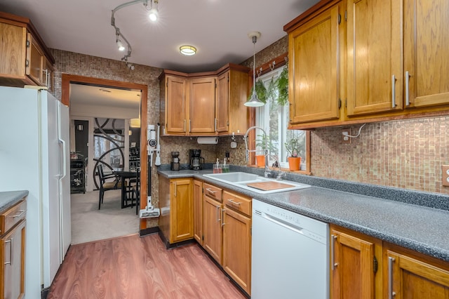 kitchen with tasteful backsplash, white appliances, sink, pendant lighting, and hardwood / wood-style flooring