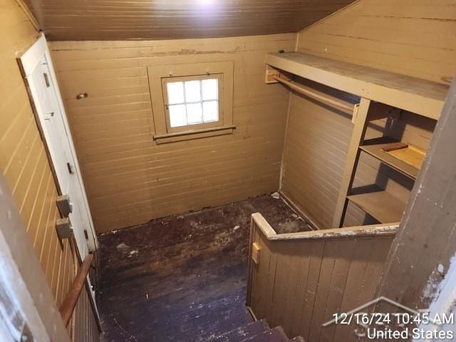 interior space featuring lofted ceiling and wooden walls