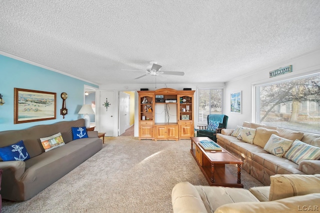 carpeted living room featuring ceiling fan, a textured ceiling, and ornamental molding