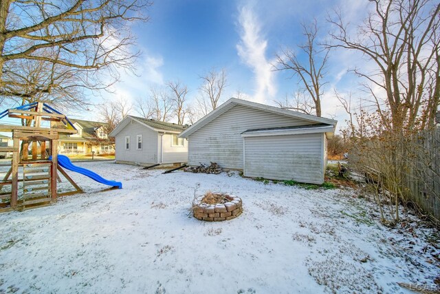 snow covered rear of property featuring a playground and an outdoor fire pit