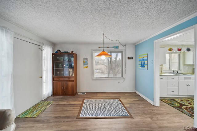 dining room with hardwood / wood-style floors, ornamental molding, and a textured ceiling