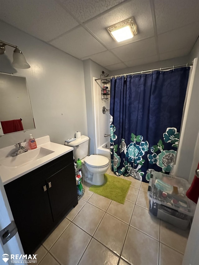 full bathroom featuring a paneled ceiling, shower / tub combo with curtain, tile patterned flooring, vanity, and toilet