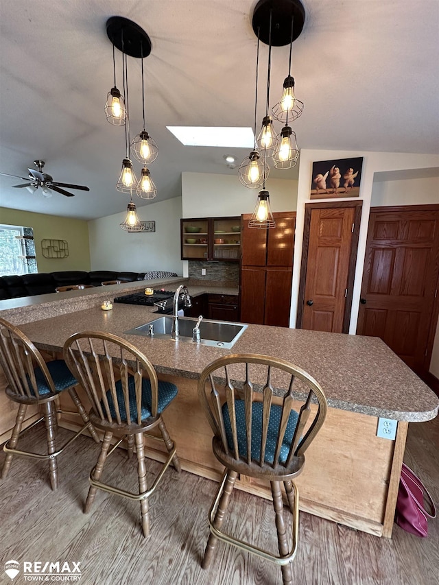 kitchen featuring wood-type flooring, a skylight, sink, and a breakfast bar area