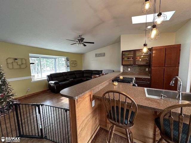 kitchen with lofted ceiling with skylight, sink, a kitchen breakfast bar, decorative backsplash, and kitchen peninsula