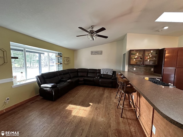 living room with lofted ceiling with skylight, ceiling fan, and dark hardwood / wood-style flooring