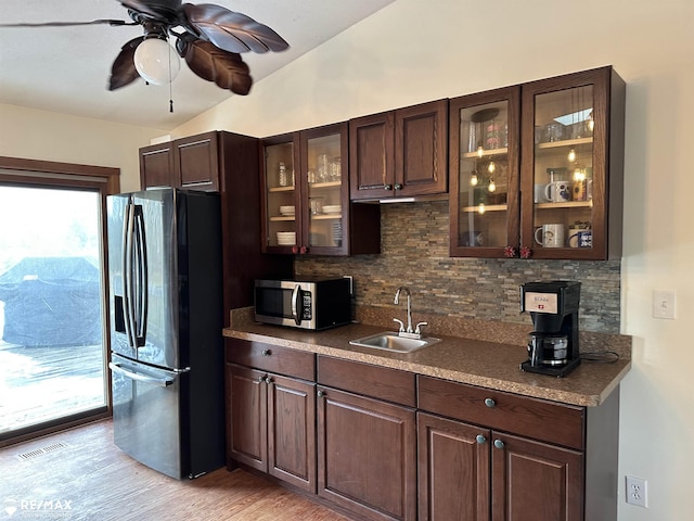 kitchen with appliances with stainless steel finishes, lofted ceiling, sink, backsplash, and dark brown cabinets