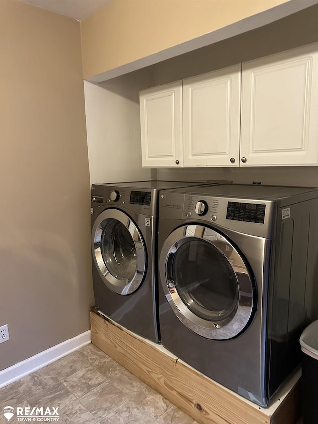 clothes washing area with washer and dryer and cabinets