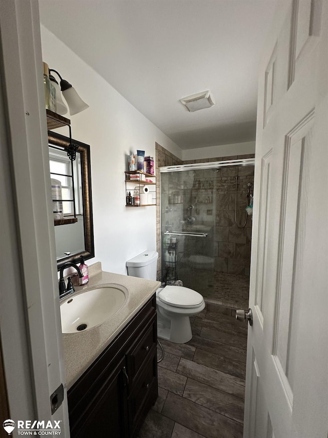 bathroom featuring vanity, walk in shower, and toilet