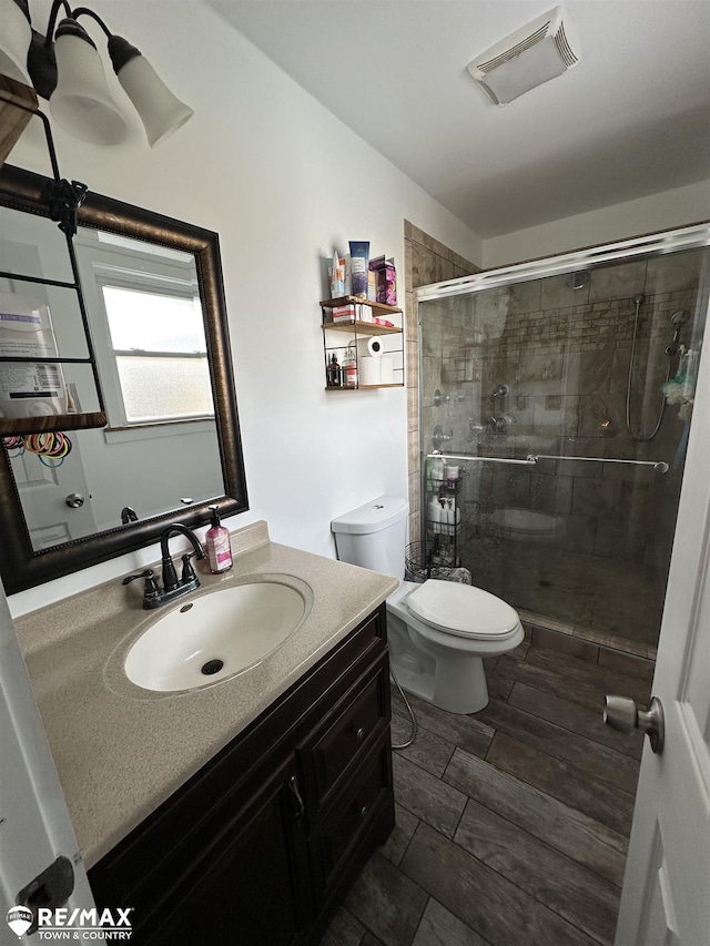 bathroom featuring vanity, toilet, and a shower with shower door