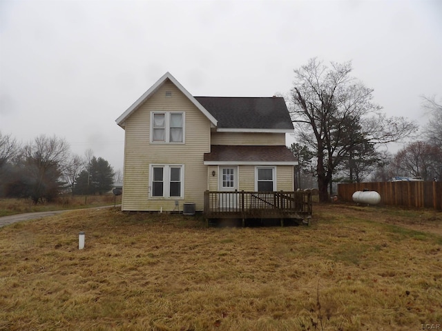 rear view of property featuring central AC unit, a yard, and a wooden deck