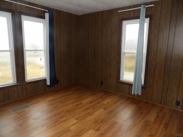 unfurnished room featuring hardwood / wood-style floors, plenty of natural light, and wood walls