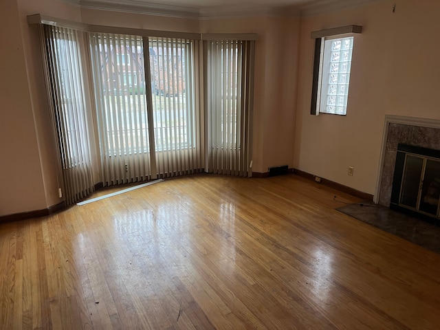 unfurnished living room with a premium fireplace, light hardwood / wood-style floors, and ornamental molding