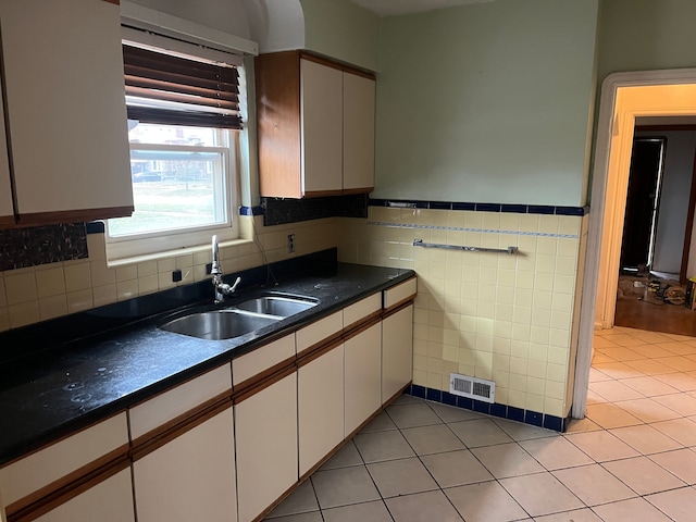 kitchen featuring white cabinets, light tile patterned flooring, tile walls, and sink