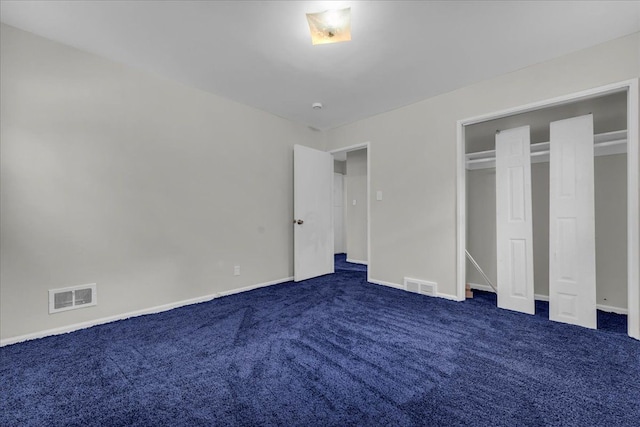 unfurnished bedroom with dark colored carpet and a closet