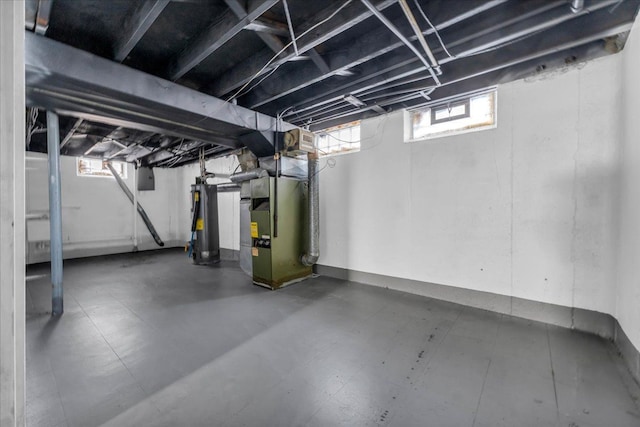 basement featuring heating unit, water heater, and a healthy amount of sunlight