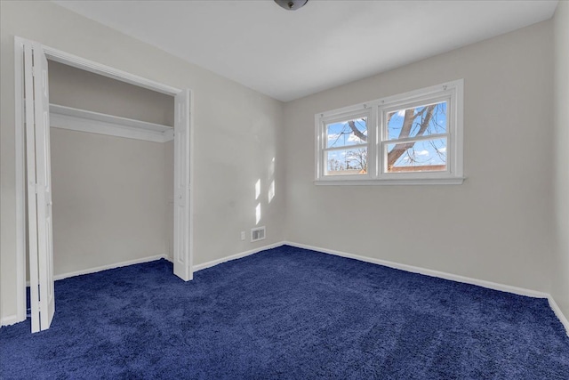 unfurnished bedroom with dark carpet and a closet