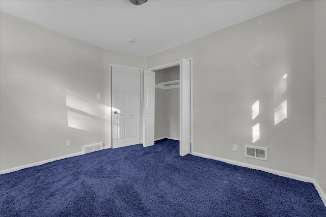 unfurnished bedroom with dark carpet and a closet