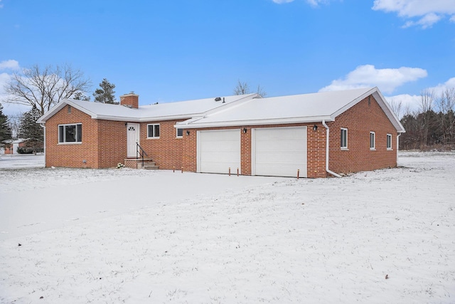 snow covered back of property featuring a garage