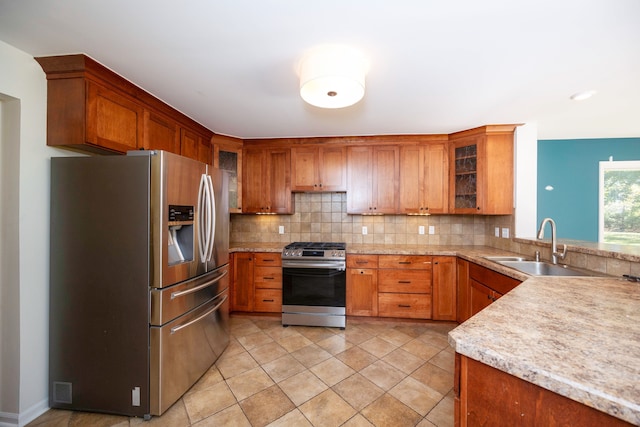 kitchen with tasteful backsplash, light stone counters, stainless steel appliances, sink, and light tile patterned flooring