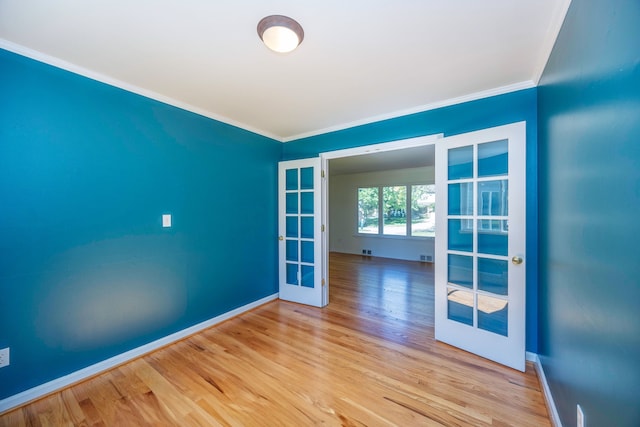 unfurnished room featuring french doors, light wood-type flooring, and crown molding