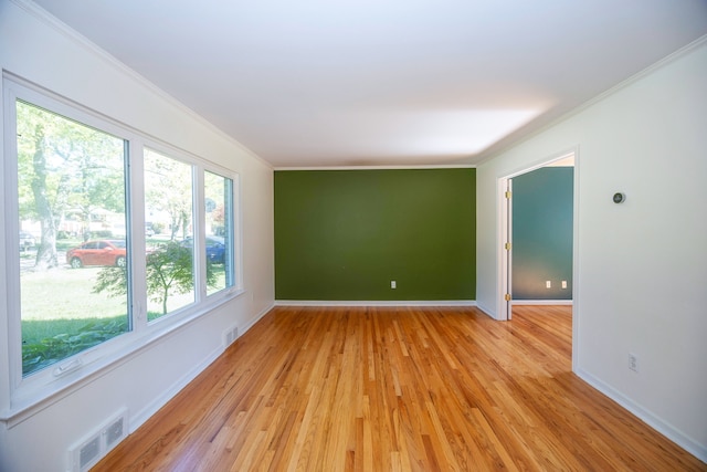 spare room featuring crown molding and light hardwood / wood-style floors