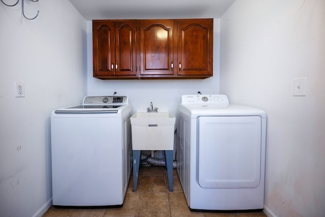 clothes washing area featuring cabinets, light tile patterned floors, washer and dryer, and sink