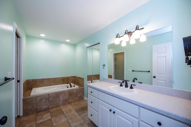 bathroom with tiled tub, tile patterned flooring, and vanity