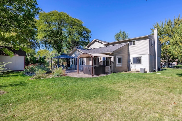 rear view of house with a gazebo, a patio area, a lawn, and a hot tub